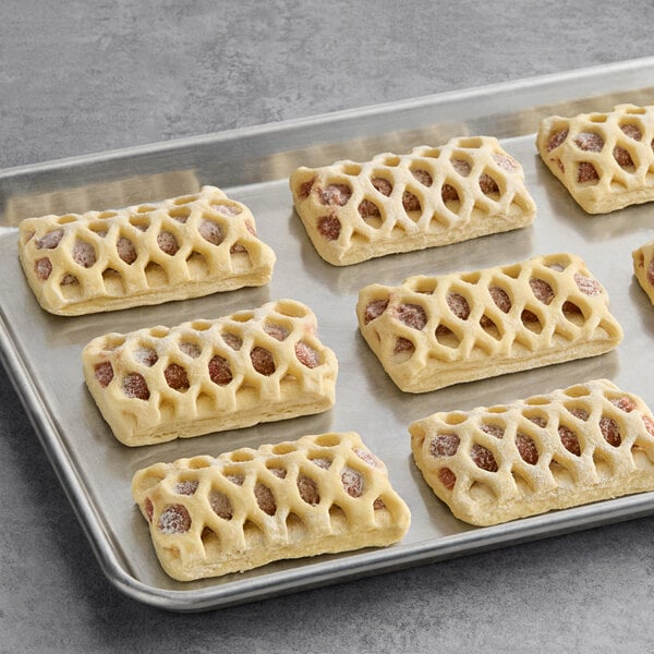 A tray of unbaked rectangular strawberry rhubarb danishes with a lattice-patterned pastry top.