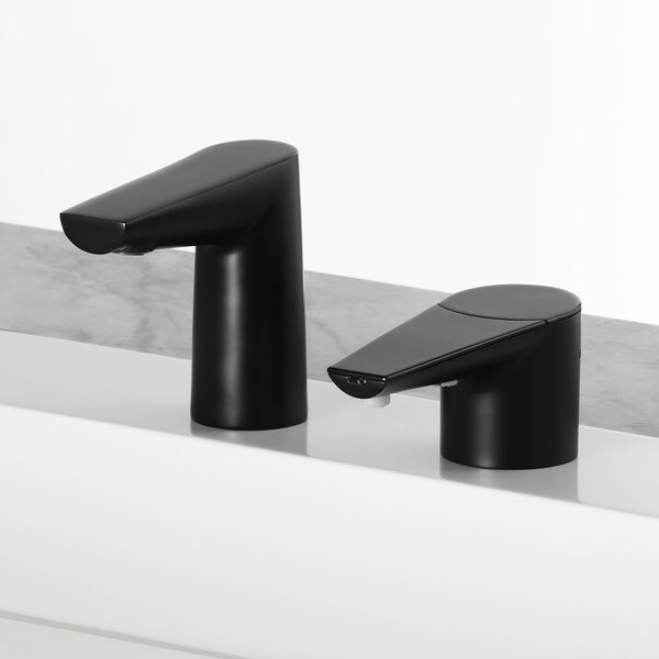 Two Bobrick matte black deck-mount bathroom faucets on a white counter.