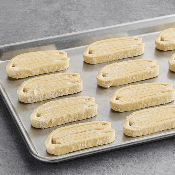 A baking sheet with several unbaked palm leaf pastries arranged in rows.