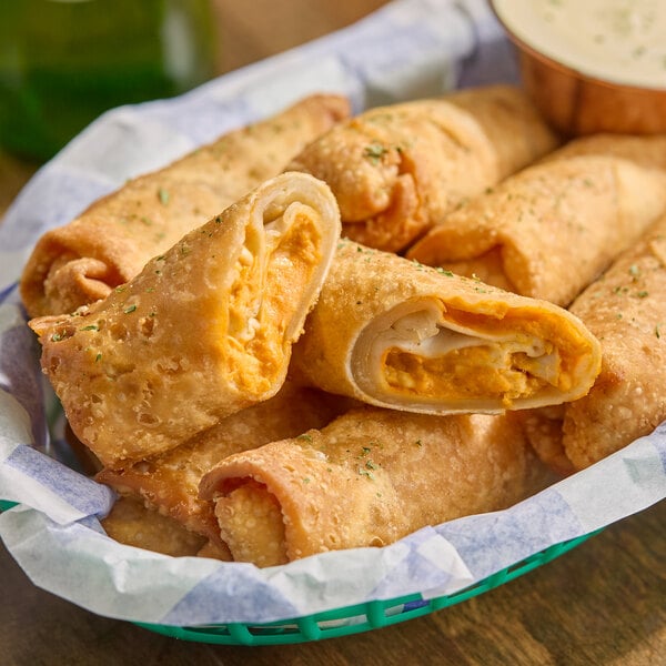 A basket of buffalo-style chicken log egg rolls with a crispy exterior and creamy filling.