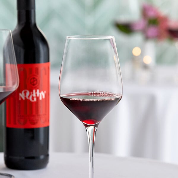 A glass of red wine next to a bottle of Noughty Non-Alcoholic Rouge Syrah.