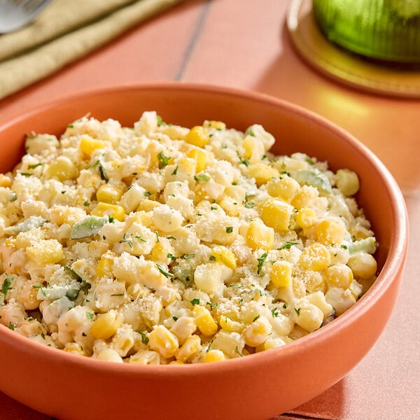 A bowl of mixed sweet yellow and white corn topped with herbs and grated cheese.