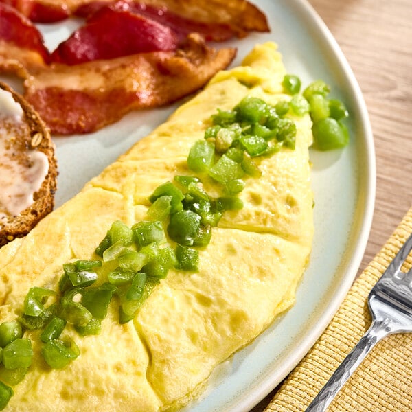 An omelet topped with diced green peppers served on a plate with bacon and a slice of bread.