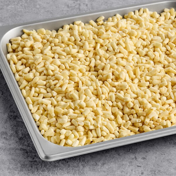 A metal tray filled with individually quick frozen (IQF) white shoepeg corn kernels.