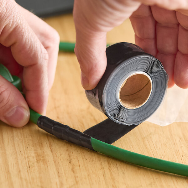 A roll of clear self-fusing silicone rubber electrical tape being wrapped around a green cable.