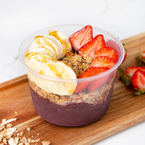 A bowl of Pitaya Foods Organic Acai Sorbet topped with banana and strawberries on a wooden tray.