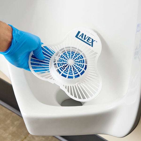 A Lavex branded deodorizing enzymatic block with a white plastic screen being placed in a urinal.