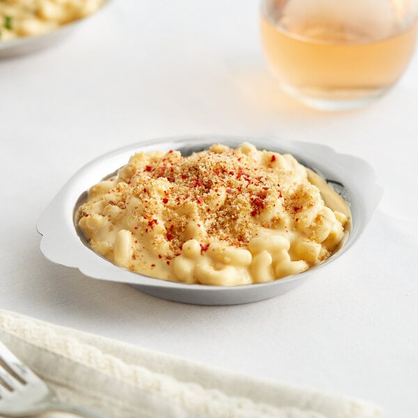 A 6 oz. stainless steel round au gratin dish filled with macaroni and cheese, topped with breadcrumbs and seasoning.