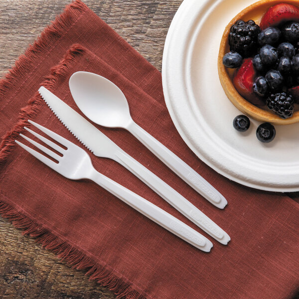 A plate with fruit and a Cutlerease white compostable plastic spoon on a napkin.