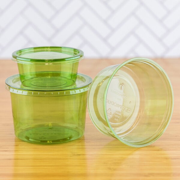 A group of Eco-Products green plastic portion cups on a wood surface.