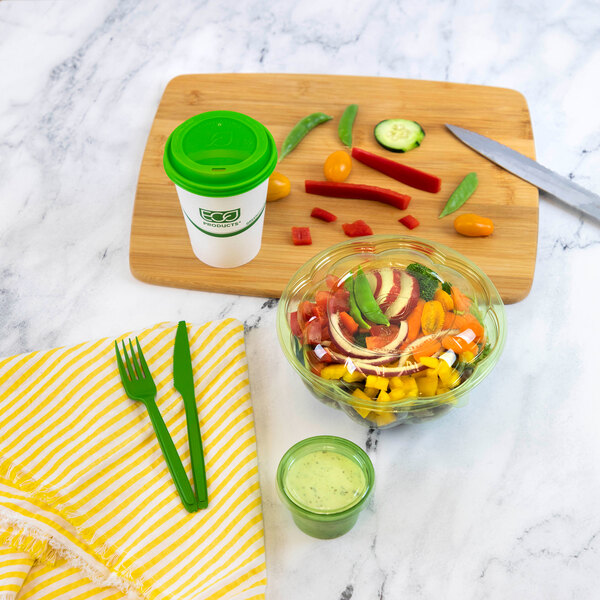A green Eco-Products Cutlerease compostable plastic knife next to a bowl of vegetables.