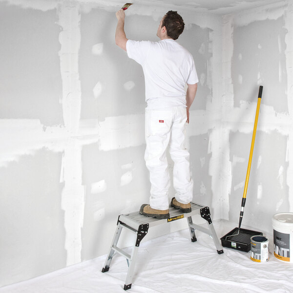 A portable aluminum work platform being used for painting or construction tasks.