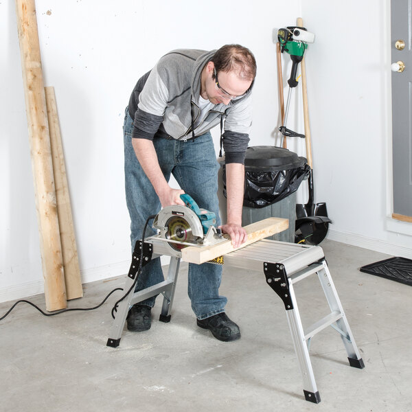 A portable aluminum work platform being used in a workshop setting.