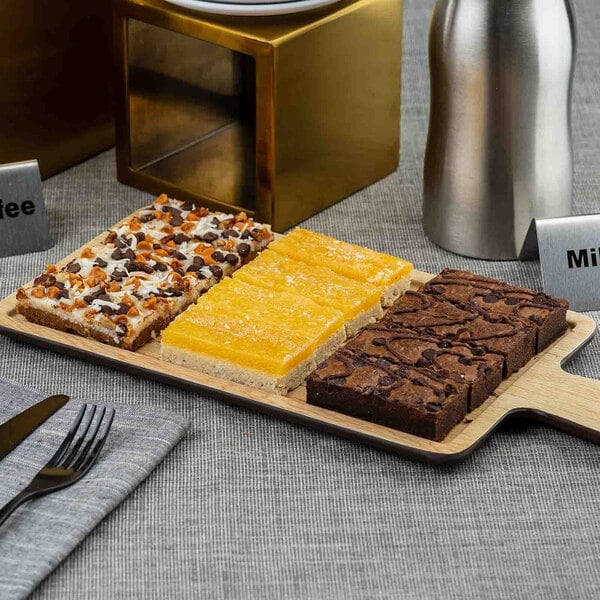 A rectangular faux wood melamine serving tray with a handle, displayed with assorted dessert bars.