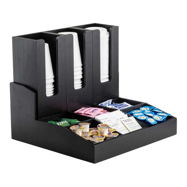 A black bamboo coffee condiment organizer with nine compartments and removable cup holders, holding cups and various condiments.