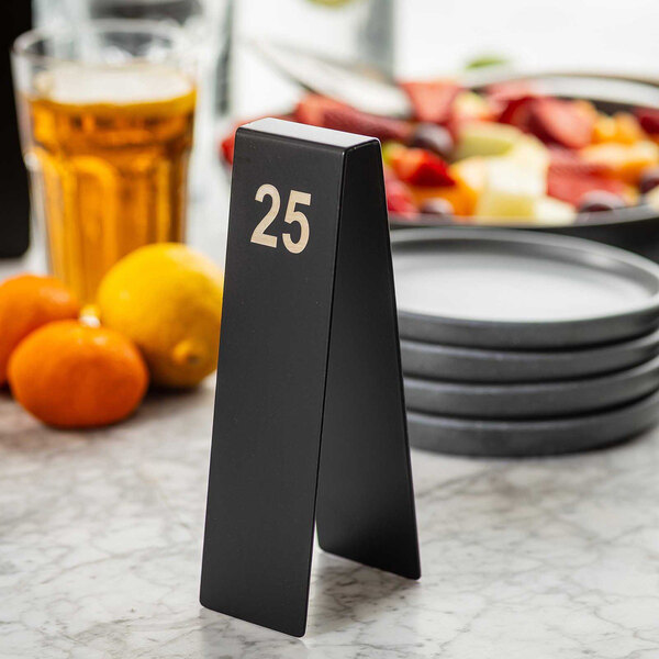 A black stainless steel table tent with the number 25 in silver, used for table numbering in restaurants.