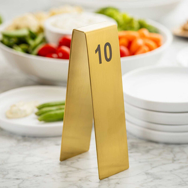 A gold stainless steel table tent with the number 10 printed in black.