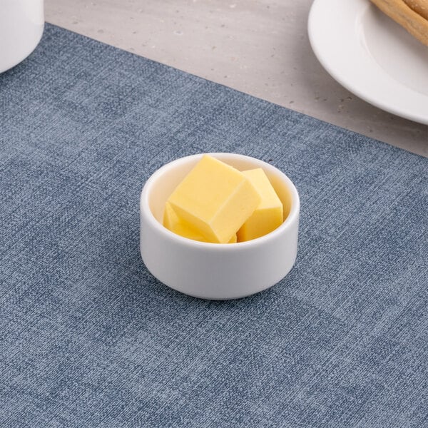 A small round white porcelain ramekin containing several cubes of butter.