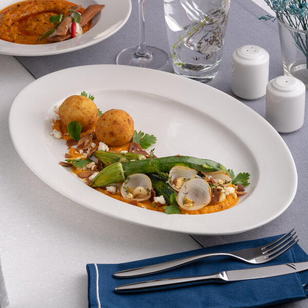 A warm white oval wide rim porcelain platter with food served on it.