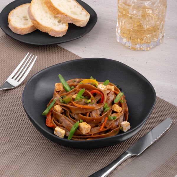 A Charcoal Grey Dots porcelain plate with noodles, vegetables, and tofu on it.