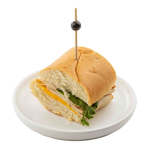 A white round melamine plate holding a sandwich with a toothpick.
