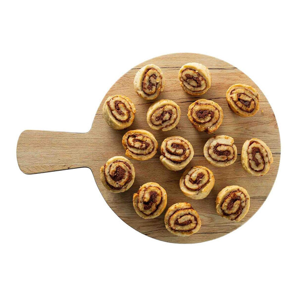 A round faux wood melamine serving board with a handle, displayed with several small cinnamon roll pastries on top.