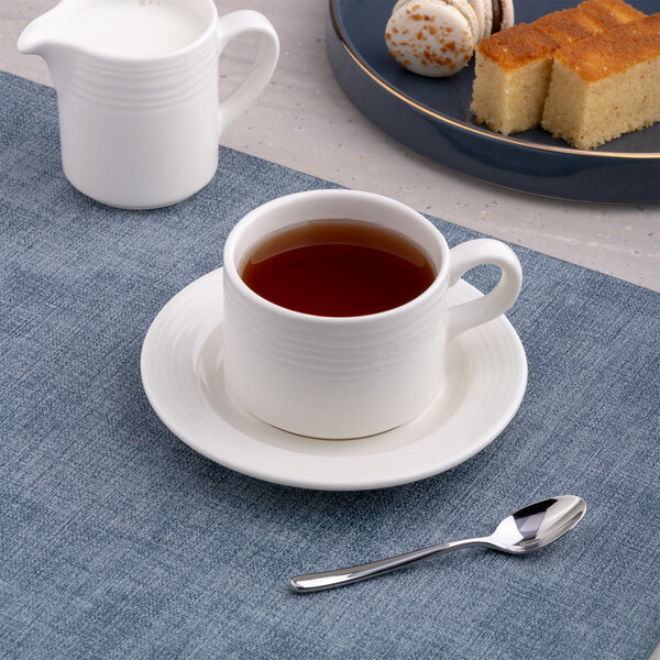 A white round embossed porcelain saucer with a wide rim, shown with a matching cup of tea.