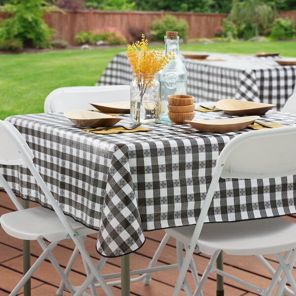 A black and white gingham vinyl table cover with a flannel back, draped over a square outdoor table.