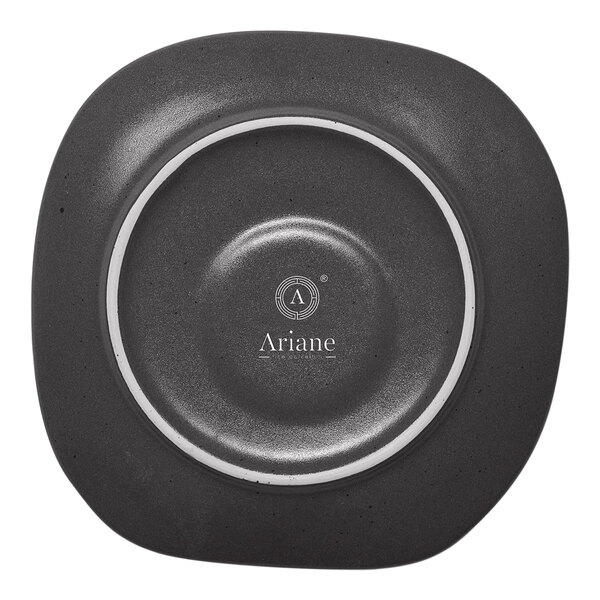 A charcoal grey Ariane porcelain saucer with black dots on it.