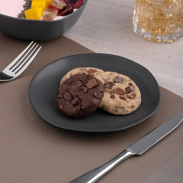 An Ariane Earth porcelain plate with a cookie and a glass of milk on it.