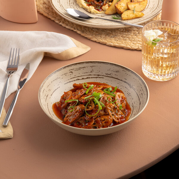 A white Ariane Tornado porcelain plate with food and a glass of wine on a table.