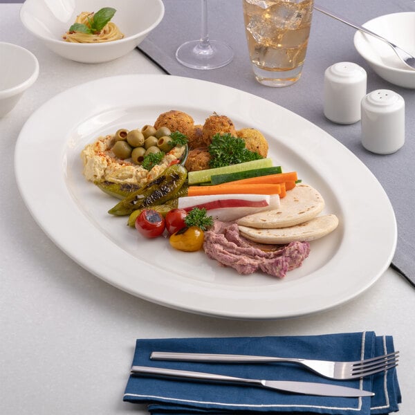 An oval wide rim porcelain platter in warm white, displayed with assorted Mediterranean appetizers.