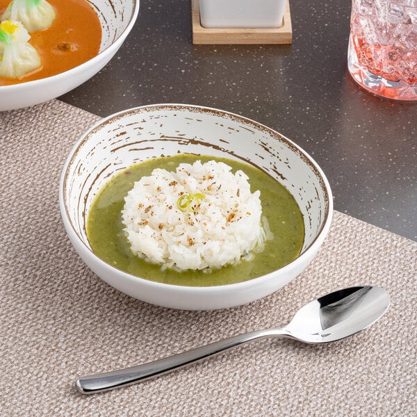 A table with two Ariane white slanted coupe bowls filled with rice and green soup.