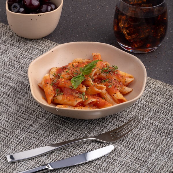 A bowl of pasta with sauce and basil in an Ariane Earth dark sand dots porcelain bowl.