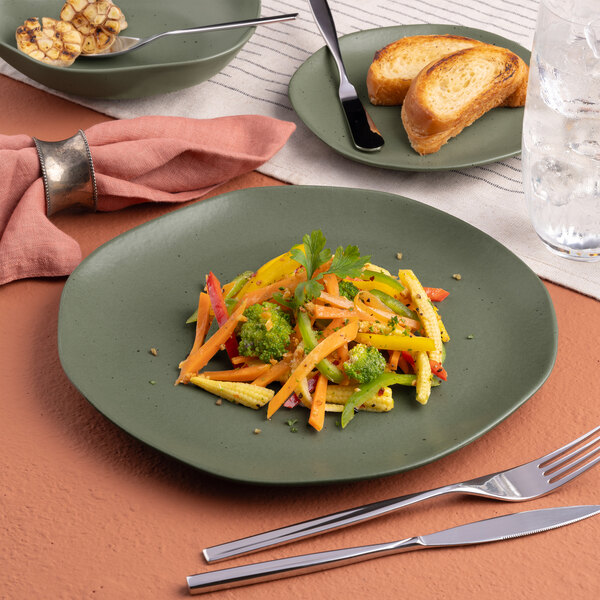 A plate of food with a knife and fork on an Ariane mist green dots porcelain plate.
