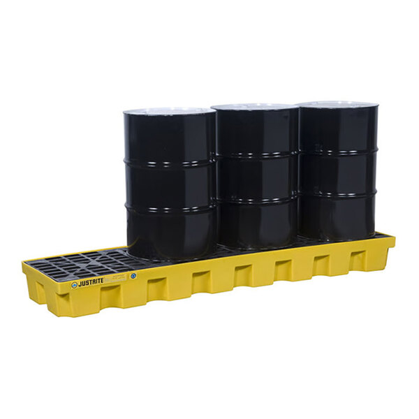 A yellow plastic in-line pallet holding four black industrial drums.