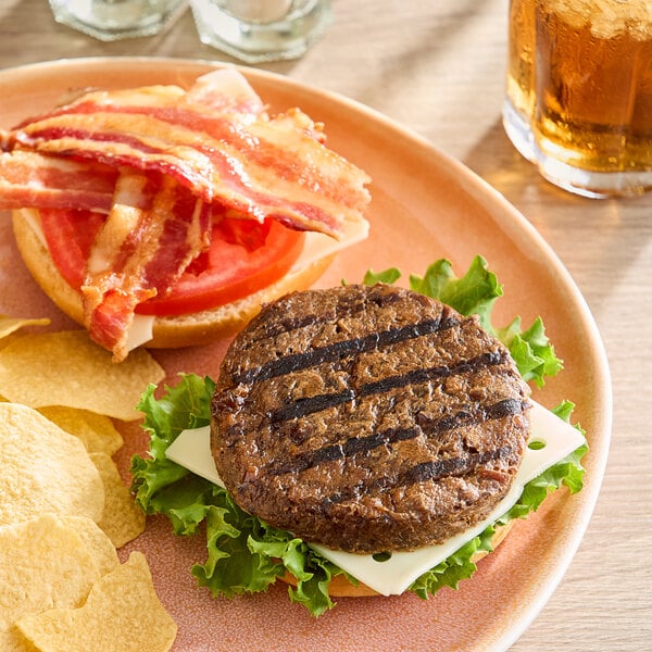 A plant-based shiitake mushroom burger with lettuce, cheese, tomato, and bacon on a bun, served with potato chips.
