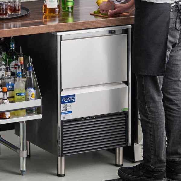 An undercounter air-cooled ice machine with a stainless steel exterior and a built-in ice storage bin.