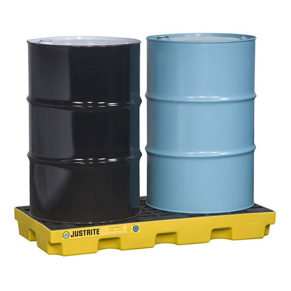 A yellow Justrite EcoPolyBlend 2-drum modular spill accumulation center holding one black and one blue drum.