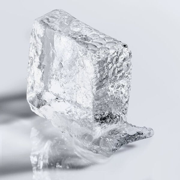 A clear half cube of ice with a textured surface, partially melting on a smooth white background.
