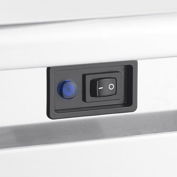 A close-up of a power switch and indicator light on a stainless steel undercounter ice machine.