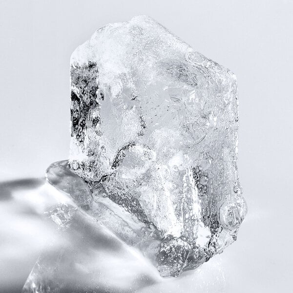A clear ice cube with visible bubbles and texture on a white background.