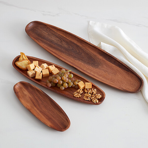 An oblong acacia wood display boat, measuring 12 inches by 4.5 inches, shown with food items for serving.