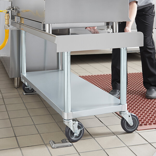 A stainless steel equipment stand with four caster wheels designed for easy mobility in commercial kitchens.