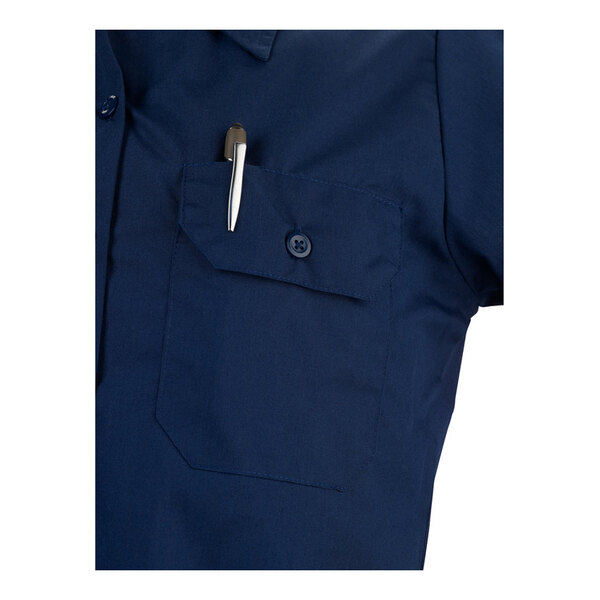 A navy blue short sleeve women's work shirt with a buttoned chest pocket holding a pen.