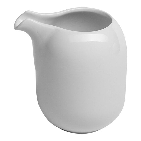 A small, handleless white porcelain creamer with a spout.