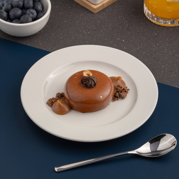 A white round porcelain plate with an embossed wide rim, shown with a dessert on top.