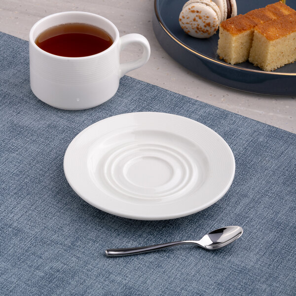 A white round embossed porcelain saucer with a wide rim.