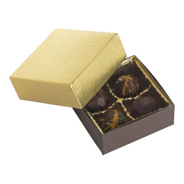 A small gold two-piece candy box with four chocolate candies inside.