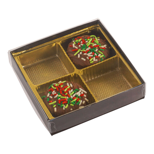 A brown and gold four-cavity candy box with a transparent lid, containing two chocolate treats with colorful sprinkles.